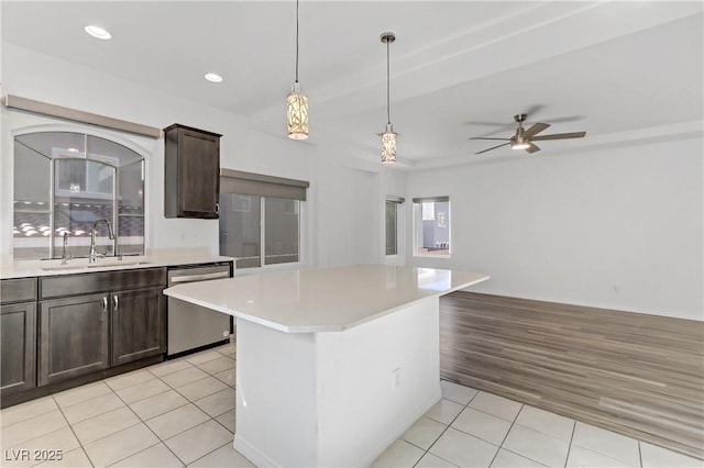 kitchen featuring sink, light tile patterned floors, dishwasher, hanging light fixtures, and a kitchen island