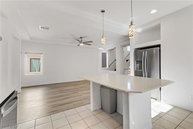 kitchen featuring decorative light fixtures, a center island, light tile patterned floors, ceiling fan, and stainless steel refrigerator with ice dispenser