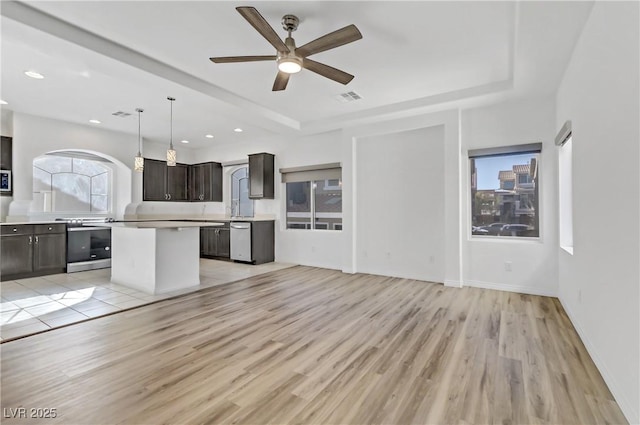 kitchen featuring hanging light fixtures, dark brown cabinets, stainless steel appliances, light hardwood / wood-style floors, and a kitchen island