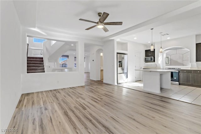 7075 Jasper Hill Way, Las Vegas, NV 89118 - unfurnished living room featuring arched walkways, light wood finished floors, a ceiling fan, stairs, and recessed lighting