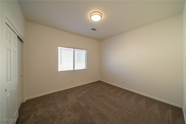 unfurnished bedroom featuring dark carpet and a closet