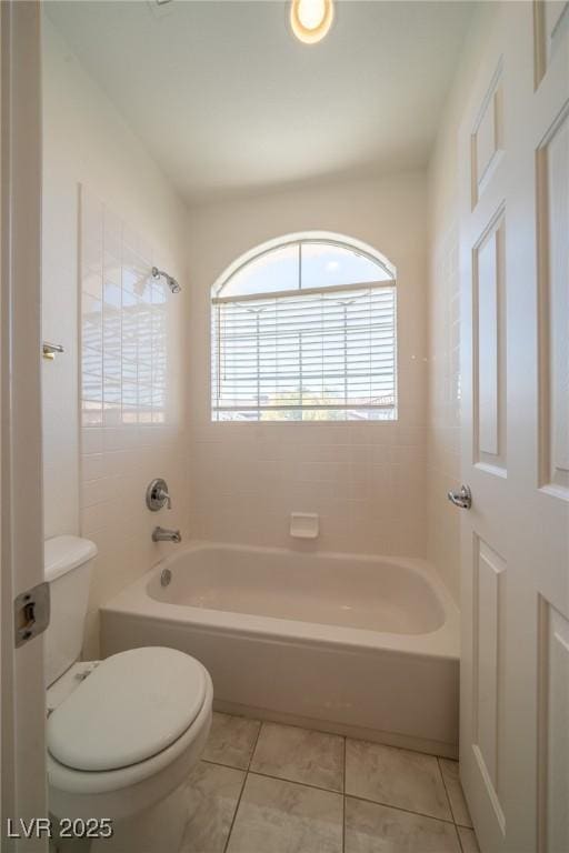 bathroom featuring tiled shower / bath, tile patterned floors, and toilet