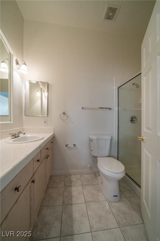 bathroom with a shower with door, vanity, tile patterned floors, and toilet