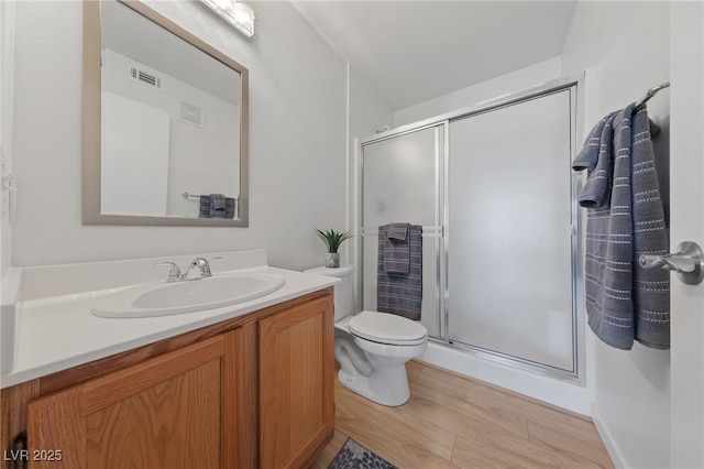 bathroom featuring vanity, wood-type flooring, a shower with door, and toilet