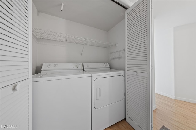 clothes washing area with separate washer and dryer and light wood-type flooring