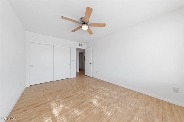 unfurnished bedroom with light wood-type flooring, ceiling fan, and a closet