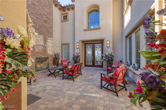 entrance to property featuring a patio and an outdoor stone fireplace