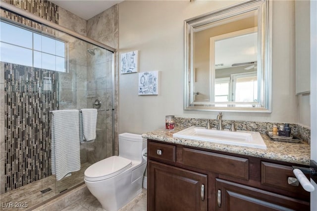 bathroom with toilet, a shower with shower door, vanity, ceiling fan, and tile patterned flooring