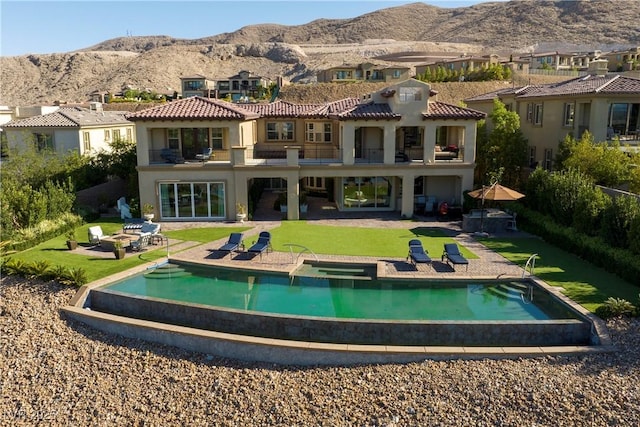 back of house with a mountain view, a lawn, and a patio area