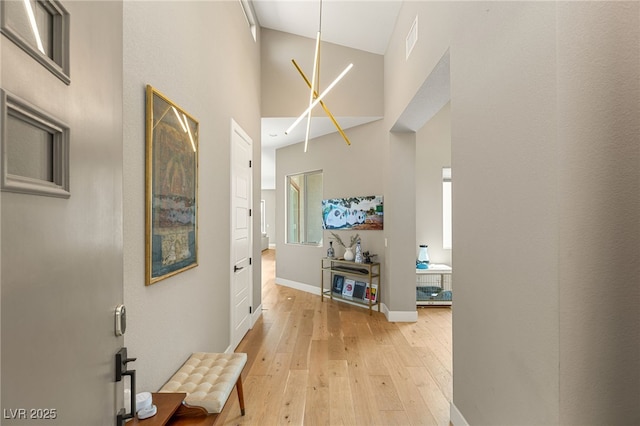 hallway with a towering ceiling and light hardwood / wood-style flooring