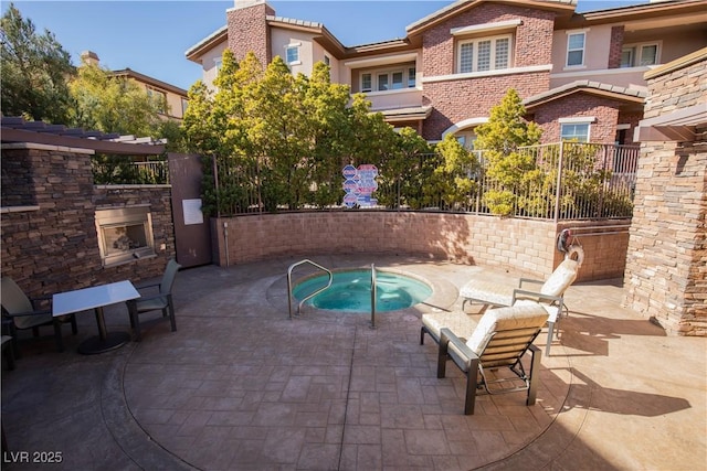 view of patio with an in ground hot tub and an outdoor stone fireplace