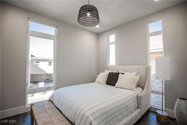 bedroom with dark hardwood / wood-style floors and multiple windows