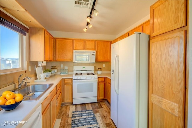 kitchen with white appliances, sink, light hardwood / wood-style flooring, and backsplash