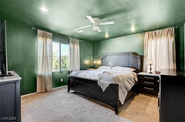 bedroom with a textured ceiling, light colored carpet, and ceiling fan