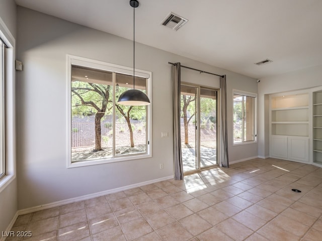 interior space featuring a healthy amount of sunlight, light tile patterned floors, and built in shelves