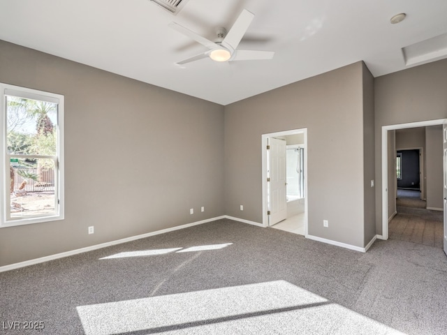 unfurnished bedroom featuring ceiling fan, light colored carpet, and ensuite bath