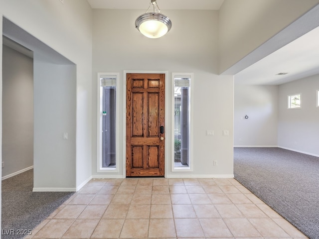 carpeted foyer entrance featuring a high ceiling