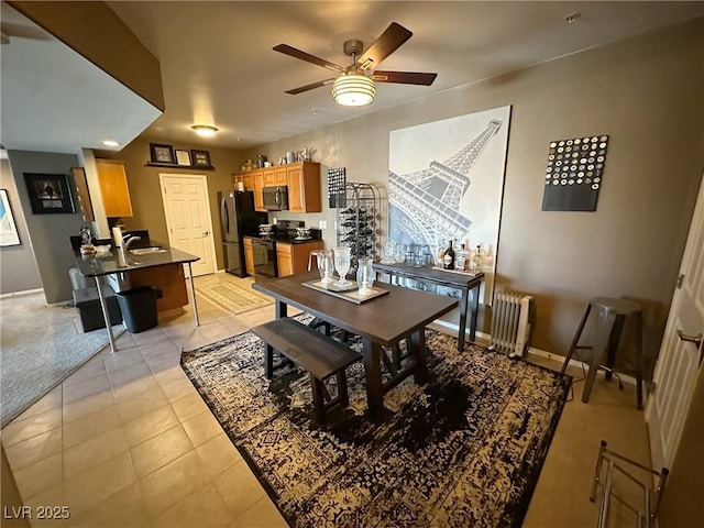 dining area with radiator, light tile patterned floors, sink, and ceiling fan