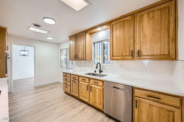 kitchen with sink, light wood-type flooring, dishwasher, light stone countertops, and backsplash