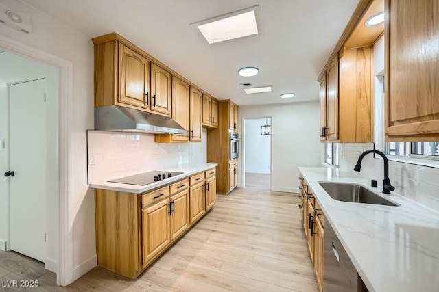 kitchen featuring sink, decorative backsplash, stainless steel appliances, light stone countertops, and light wood-type flooring