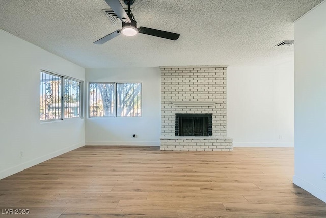 unfurnished living room featuring ceiling fan, a textured ceiling, a fireplace, and light wood-type flooring