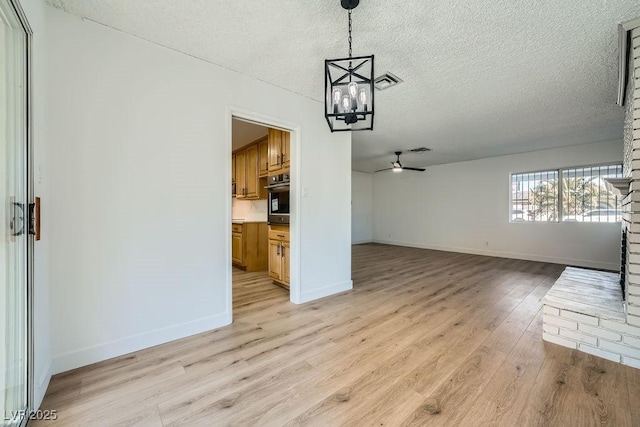 interior space featuring ceiling fan with notable chandelier, a textured ceiling, and light wood-type flooring