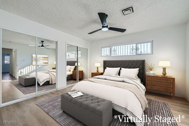 bedroom featuring multiple closets, ceiling fan, hardwood / wood-style floors, and a textured ceiling