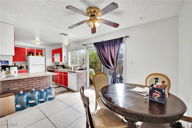 tiled dining room with ceiling fan and a textured ceiling