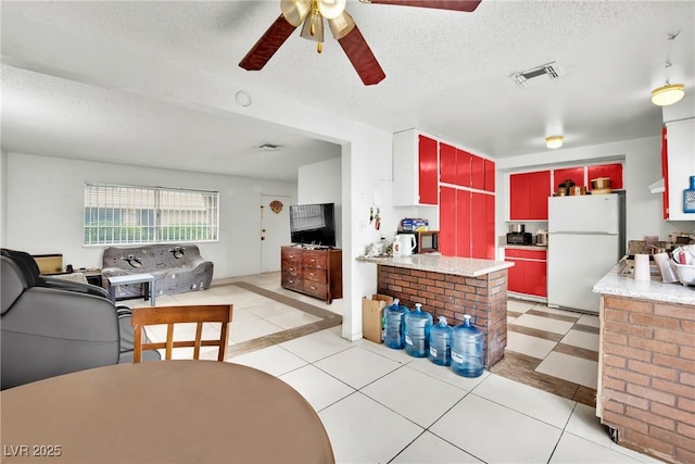 kitchen with white refrigerator, ceiling fan, light tile patterned floors, and a textured ceiling