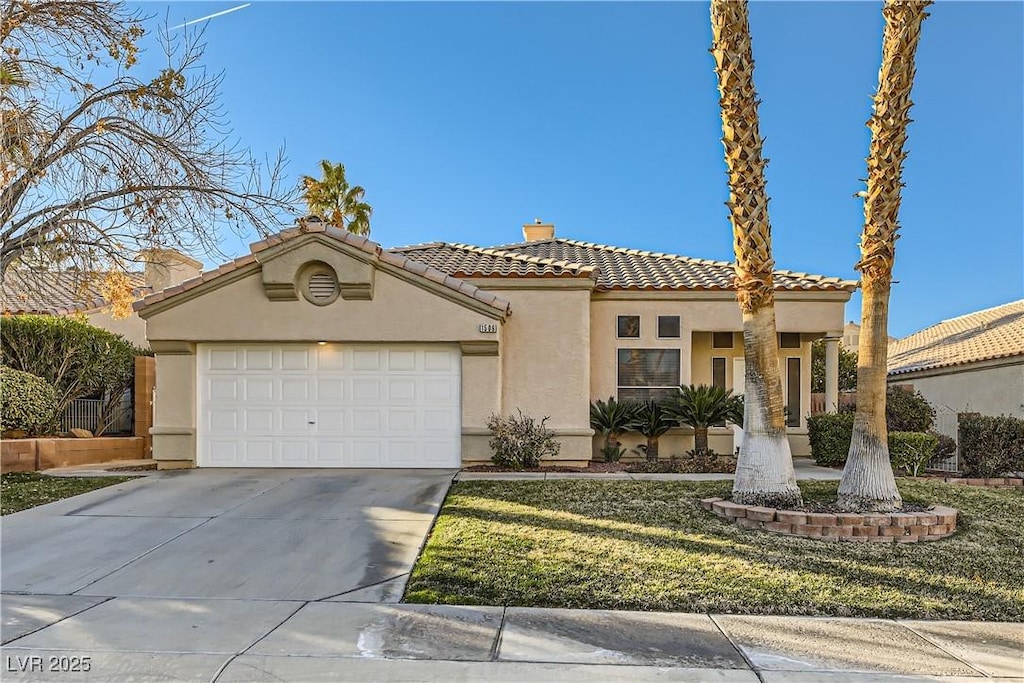 mediterranean / spanish home with a garage and a front lawn