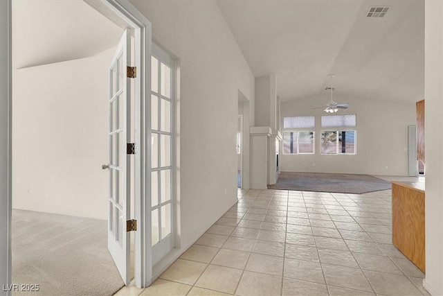 corridor featuring french doors, light tile patterned flooring, and vaulted ceiling