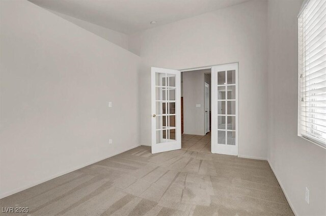 unfurnished room featuring french doors and light carpet