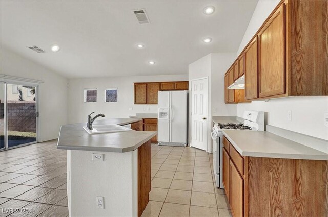 kitchen featuring white appliances, sink, an island with sink, and light tile patterned floors