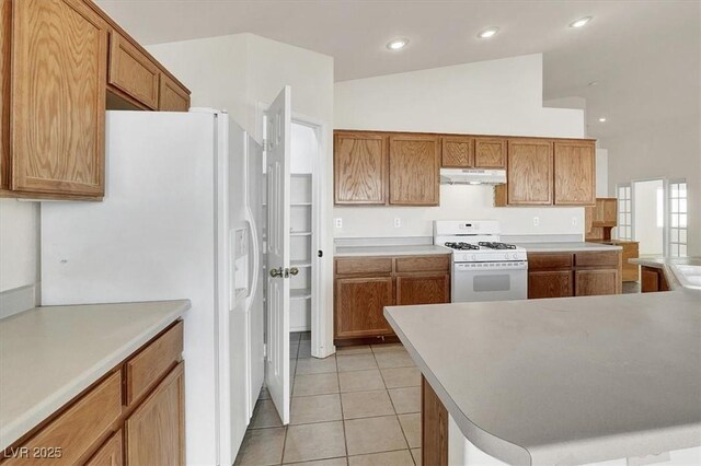 kitchen with light tile patterned floors, white appliances, and vaulted ceiling