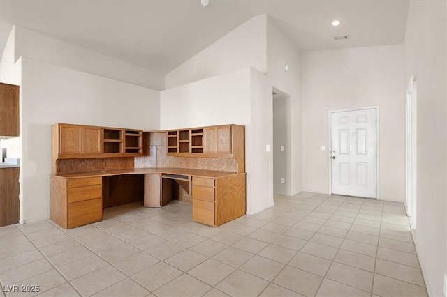 kitchen with built in desk, light tile patterned floors, and high vaulted ceiling