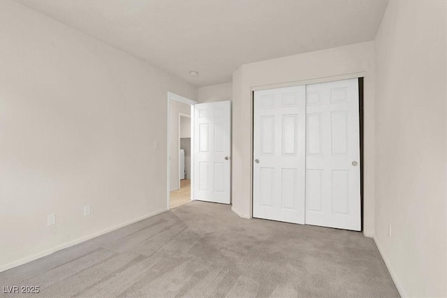 unfurnished bedroom with light carpet and a closet