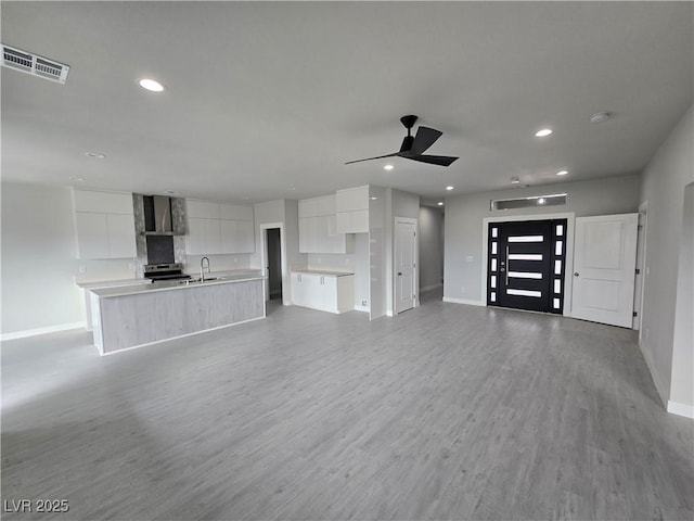 unfurnished living room featuring sink, ceiling fan, and light wood-type flooring