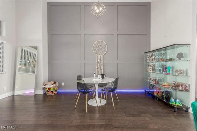 dining room with a heating unit, a decorative wall, baseboards, and wood finished floors