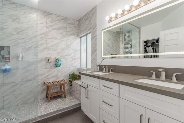 bathroom with a walk in closet, double vanity, a walk in shower, and a sink