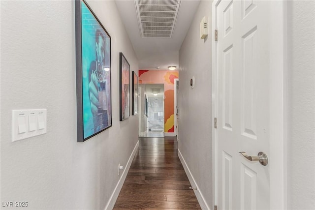 hall featuring baseboards, visible vents, and dark wood finished floors