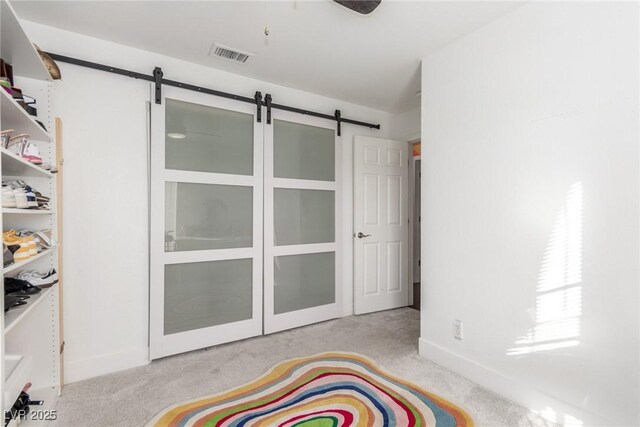 bedroom with a barn door and light carpet