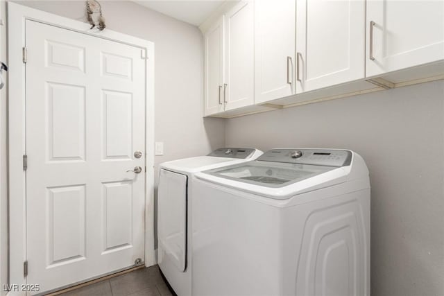 laundry area featuring cabinets, washing machine and dryer, and dark tile patterned flooring