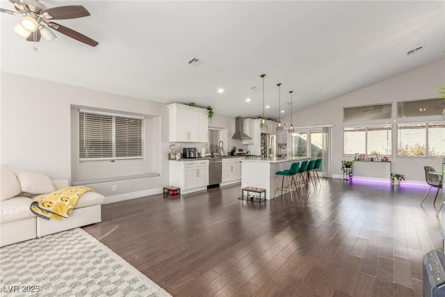 living area with dark wood-style floors, lofted ceiling, visible vents, and baseboards