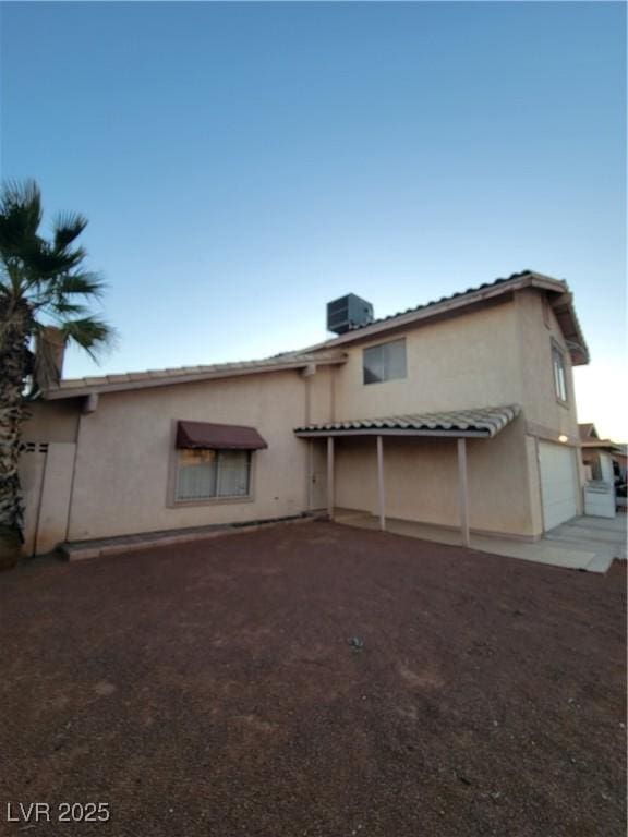 back of house featuring a garage and central AC unit