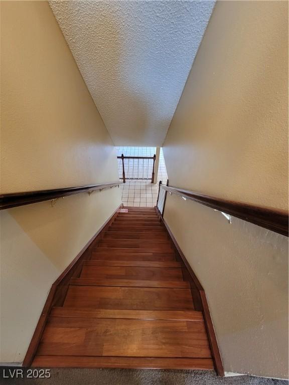 stairway featuring wood-type flooring and a textured ceiling