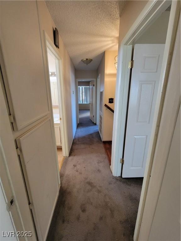 hallway featuring light colored carpet and a textured ceiling