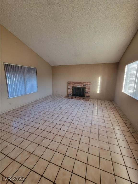 unfurnished living room featuring vaulted ceiling, a textured ceiling, and a fireplace