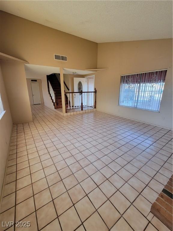 tiled spare room with lofted ceiling and a textured ceiling