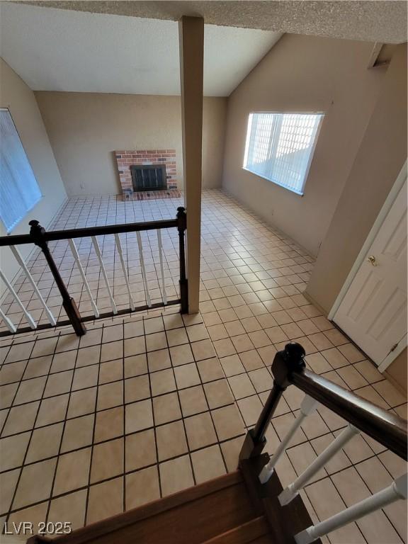 stairway featuring tile patterned flooring, vaulted ceiling, and a textured ceiling