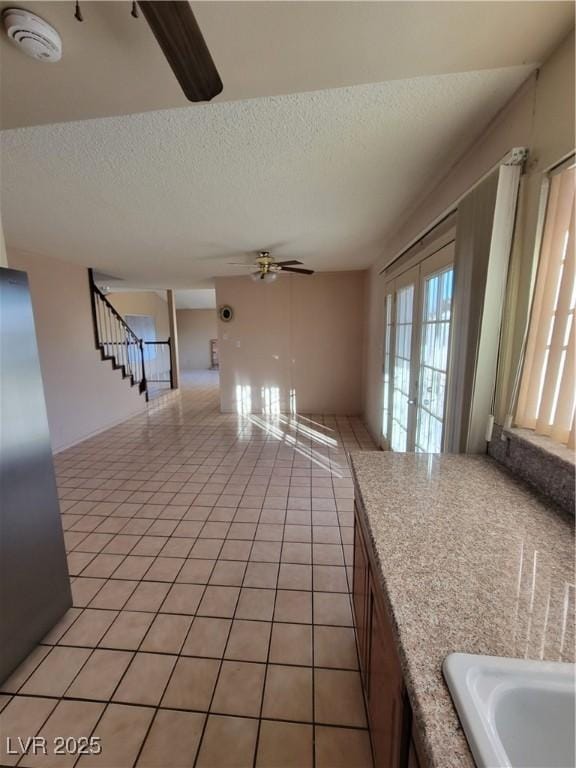 interior space featuring french doors, ceiling fan, a textured ceiling, and light tile patterned floors